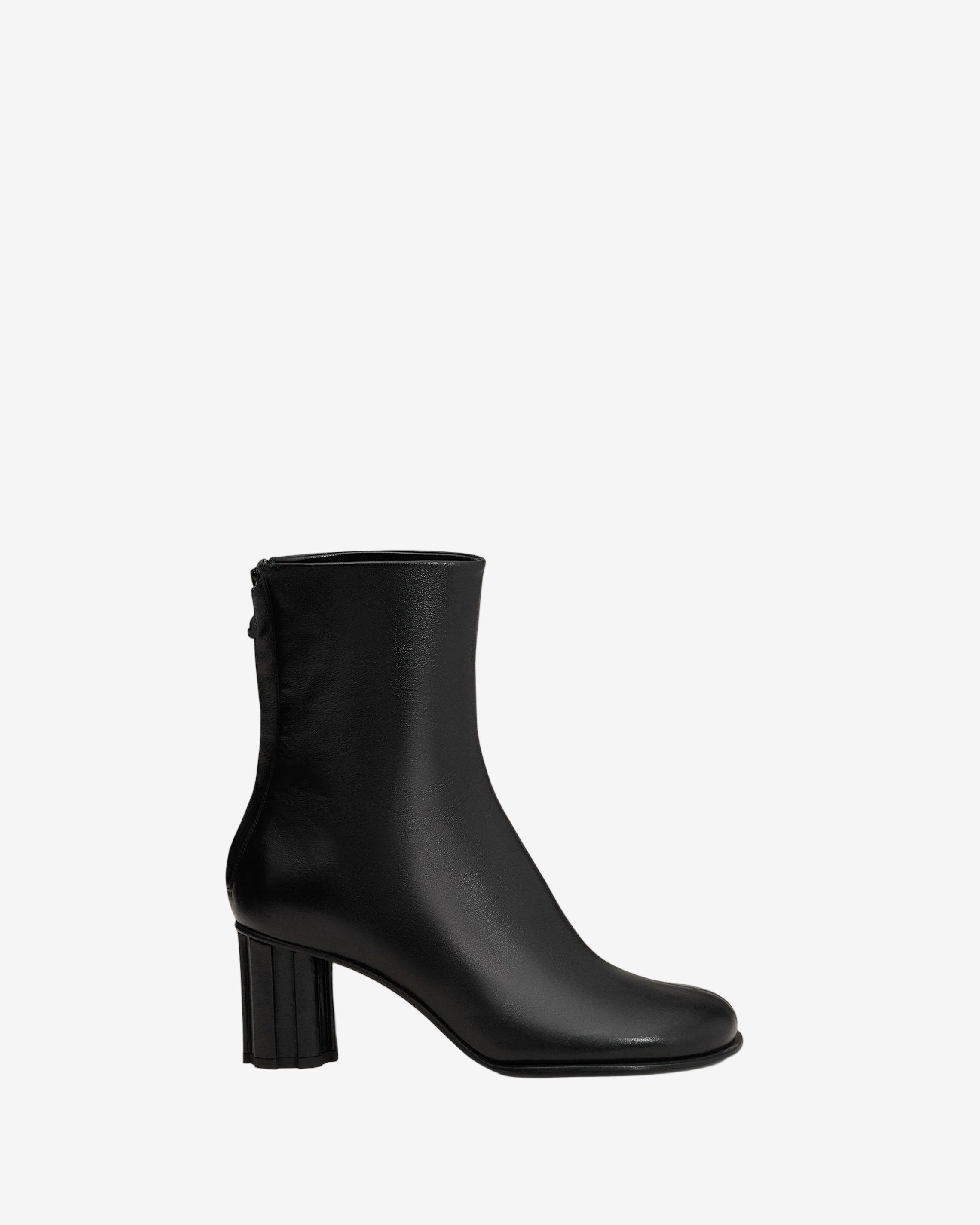 Black ankle boot on a light beige background