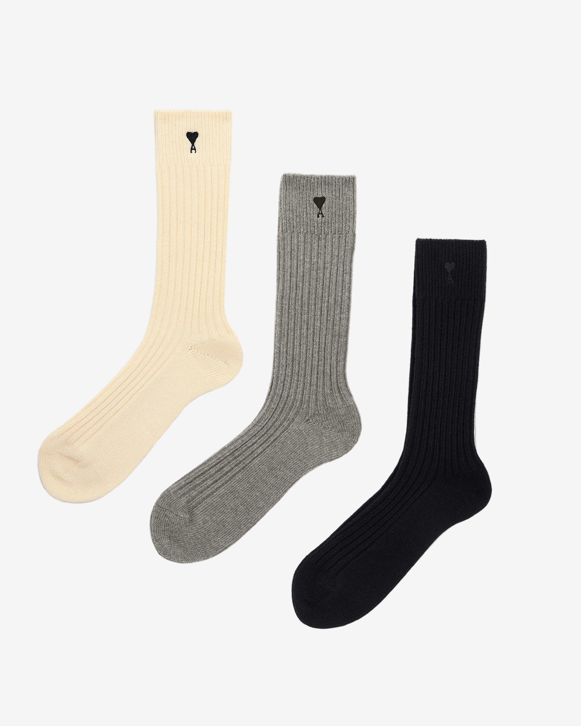 Three pairs of socks in beige, gray, and black on a light beige background