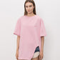 A light pink short-sleeve t-shirt with a small tonal pink ATTICO' logo on the left chest, displayed on a neutral light gray background.