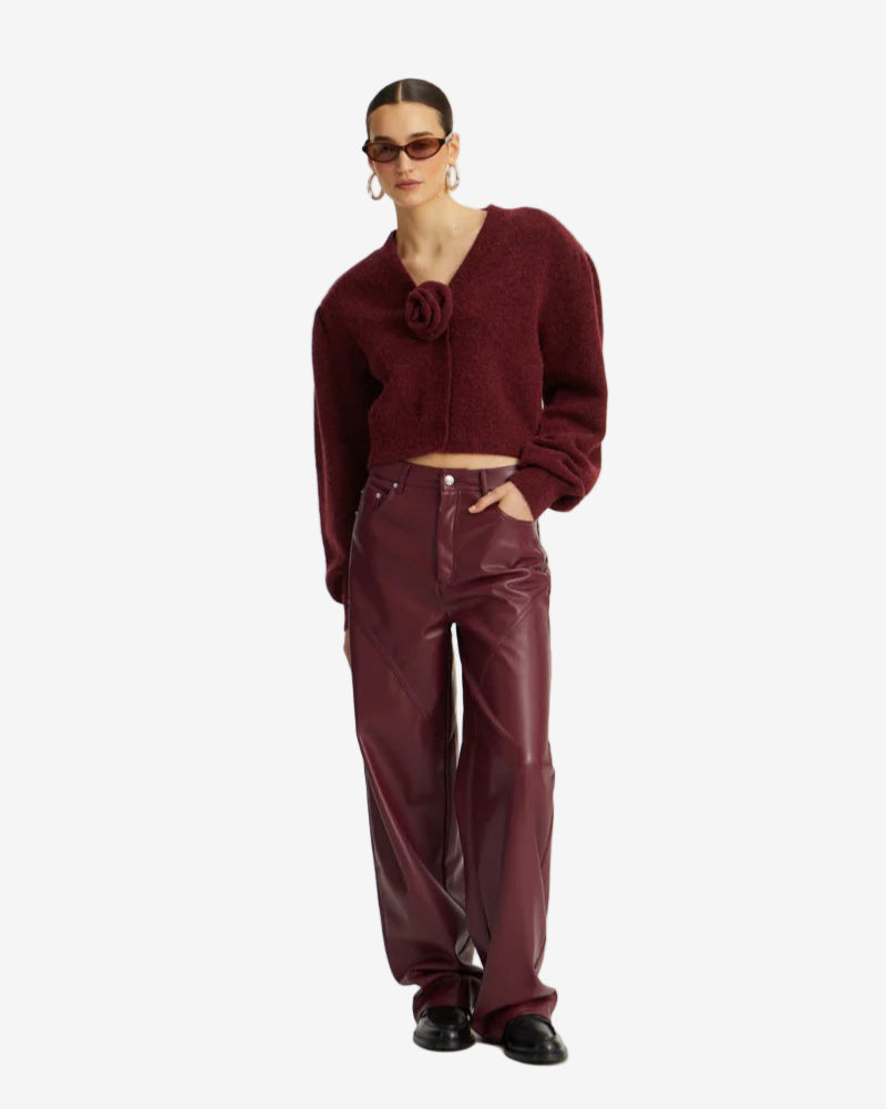 Person wearing a burgundy sweater and pants on a white background