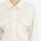 Close-up of a person wearing a cream-colored shirt with a collar.