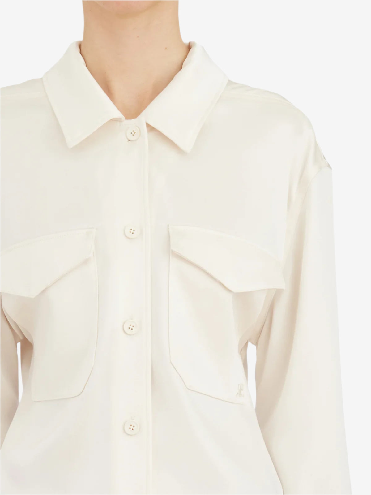 Close-up of a person wearing a cream-colored shirt with a collar.