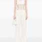 Person wearing a white sleeveless top with mesh design and matching pants on a white background