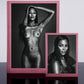Two framed black and white portraits of a woman, one nude and one wearing a top, on a reflective surface with a light gray background.