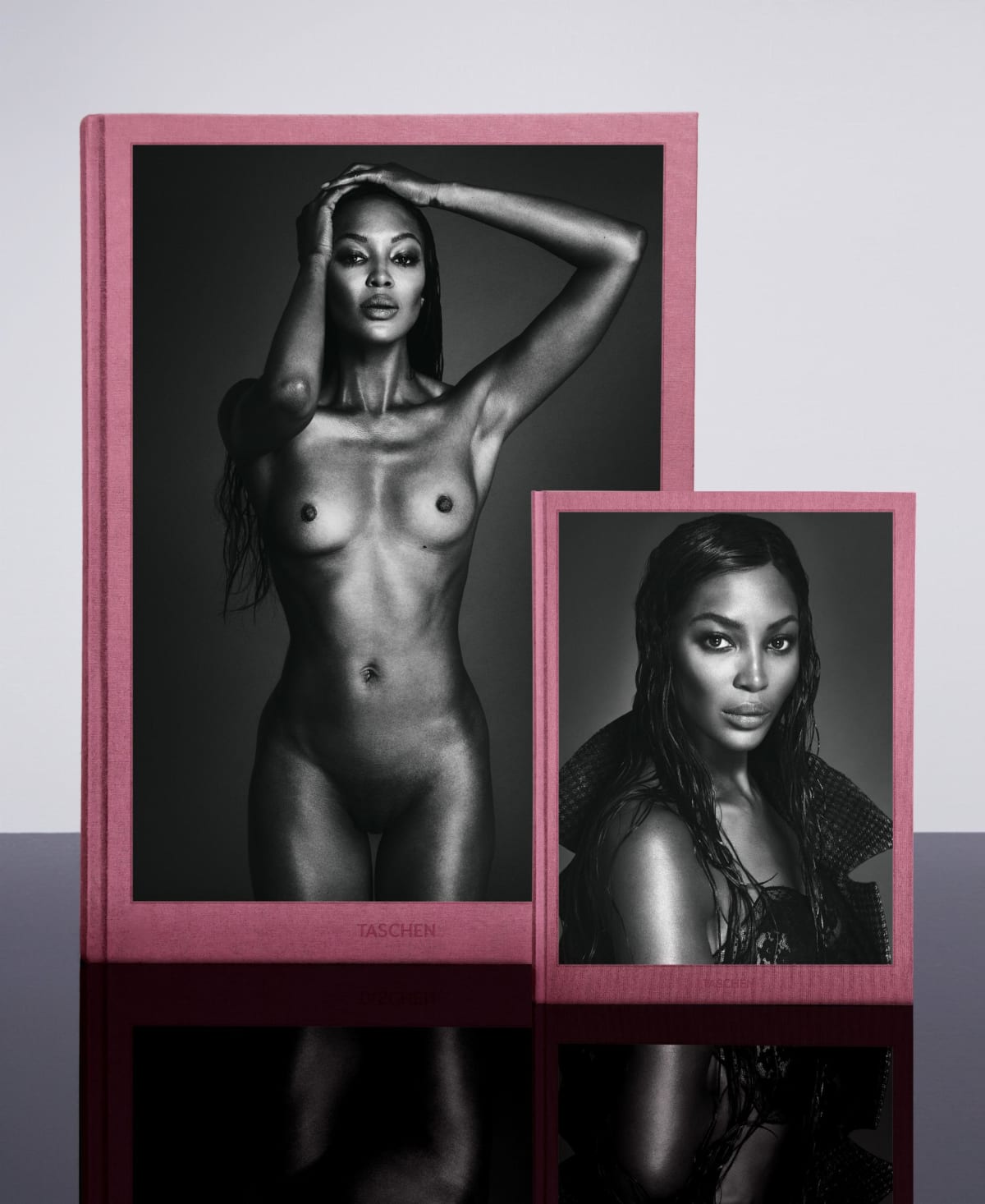 Two framed black and white portraits of a woman, one nude and one wearing a top, on a reflective surface with a light gray background.