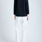 Person wearing a black top and white pants on a plain background