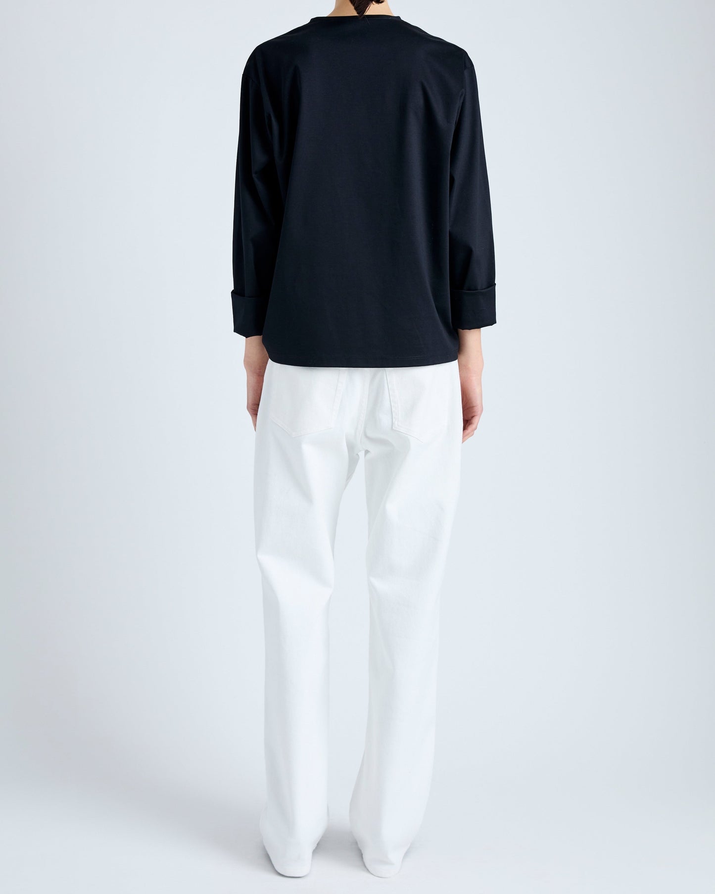 Person wearing a black top and white pants on a plain background