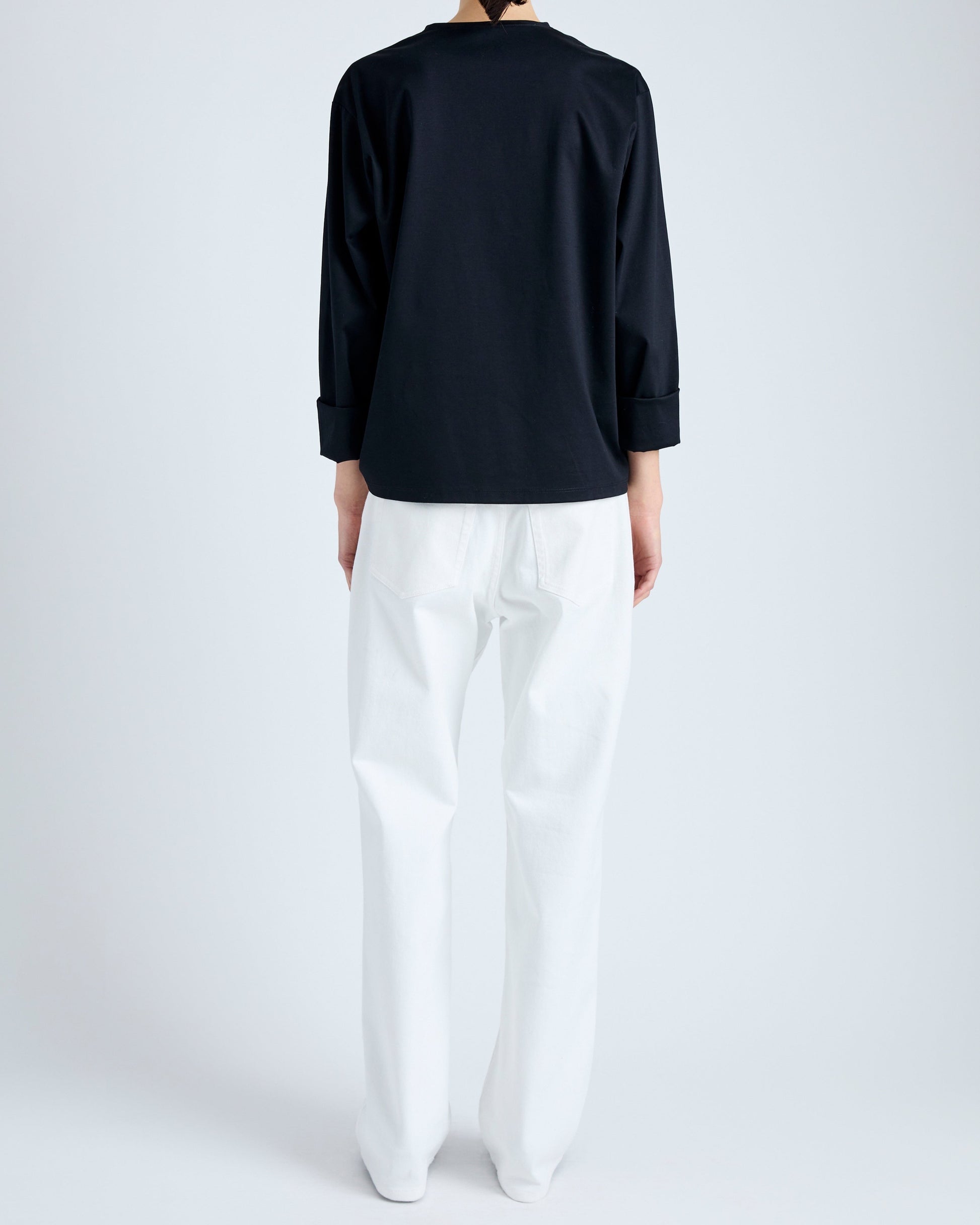 Person wearing a black top and white pants on a plain background