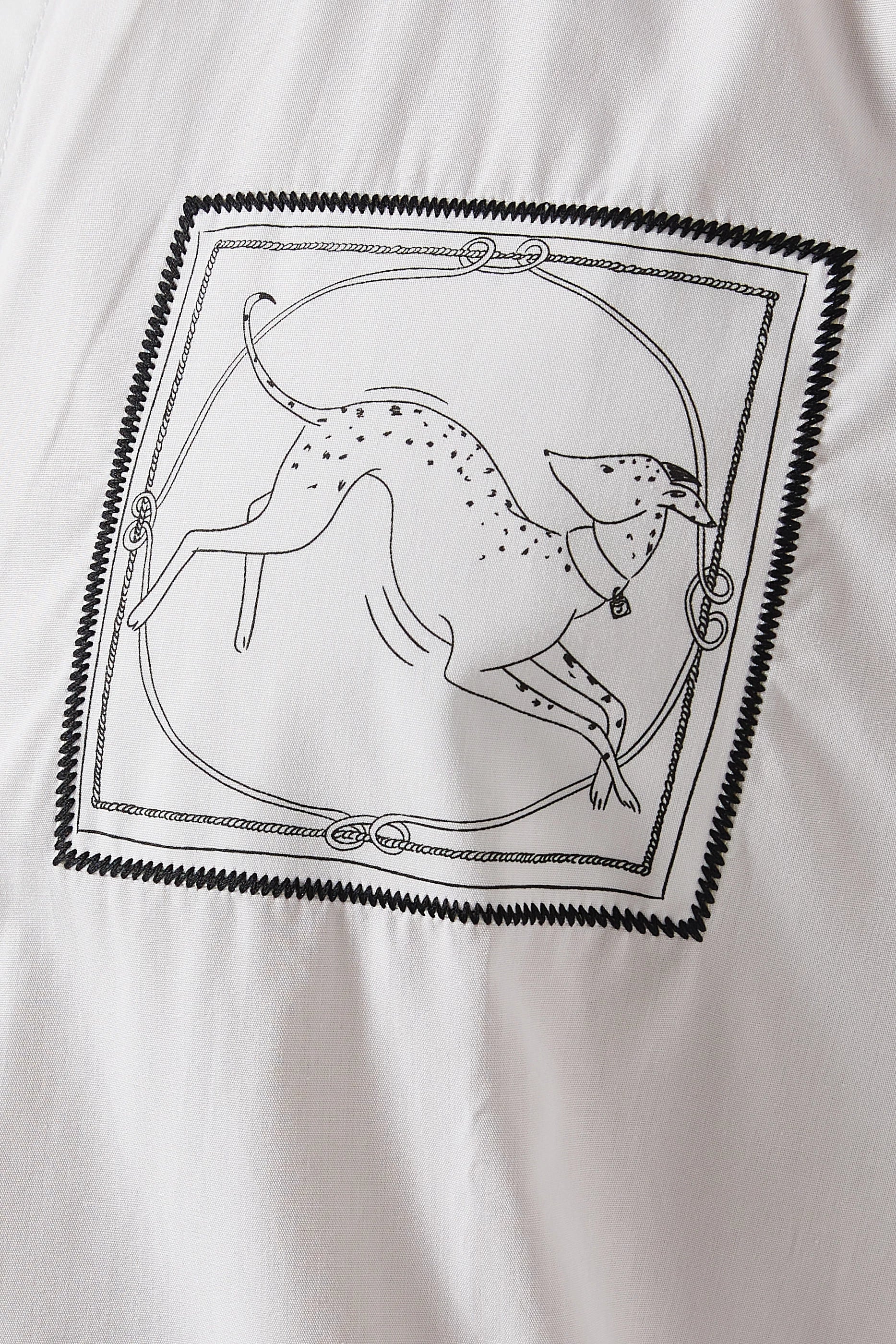 White shirt with a small black logo on the chest against a white background