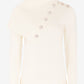 Cream-colored sweater with pearl buttons on a white background