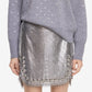 Person wearing a gray sweater with pearl embellishments and a silver sequin skirt on a white background