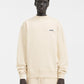 Person wearing a beige sweatshirt with a logo on a white background