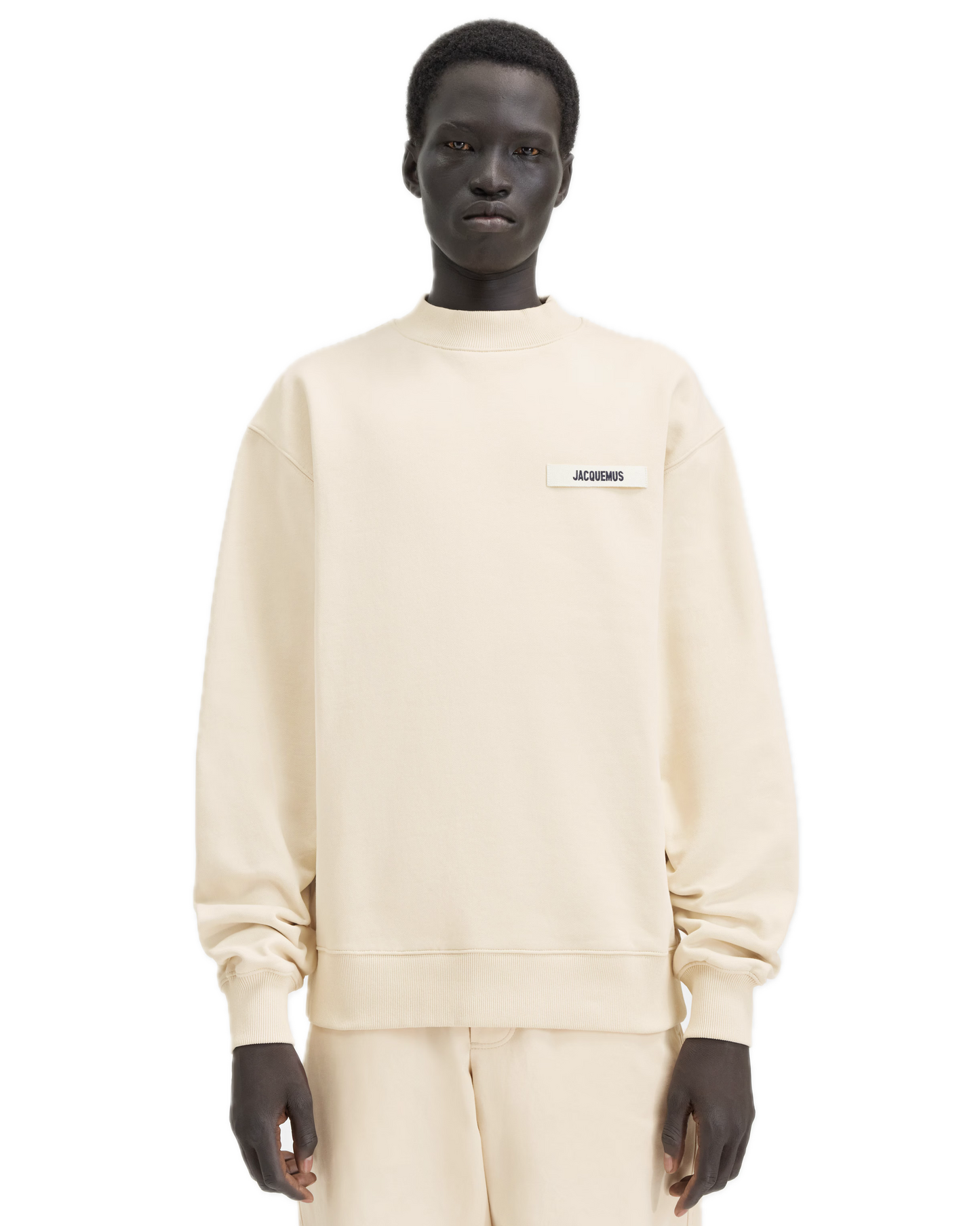 Person wearing a beige sweatshirt with a logo on a white background