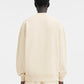 Person wearing a beige sweatshirt with a logo on a white background