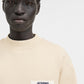 Person wearing a beige sweatshirt with a logo on a white background