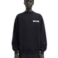 Person wearing a black sweatshirt with a logo on a white background
