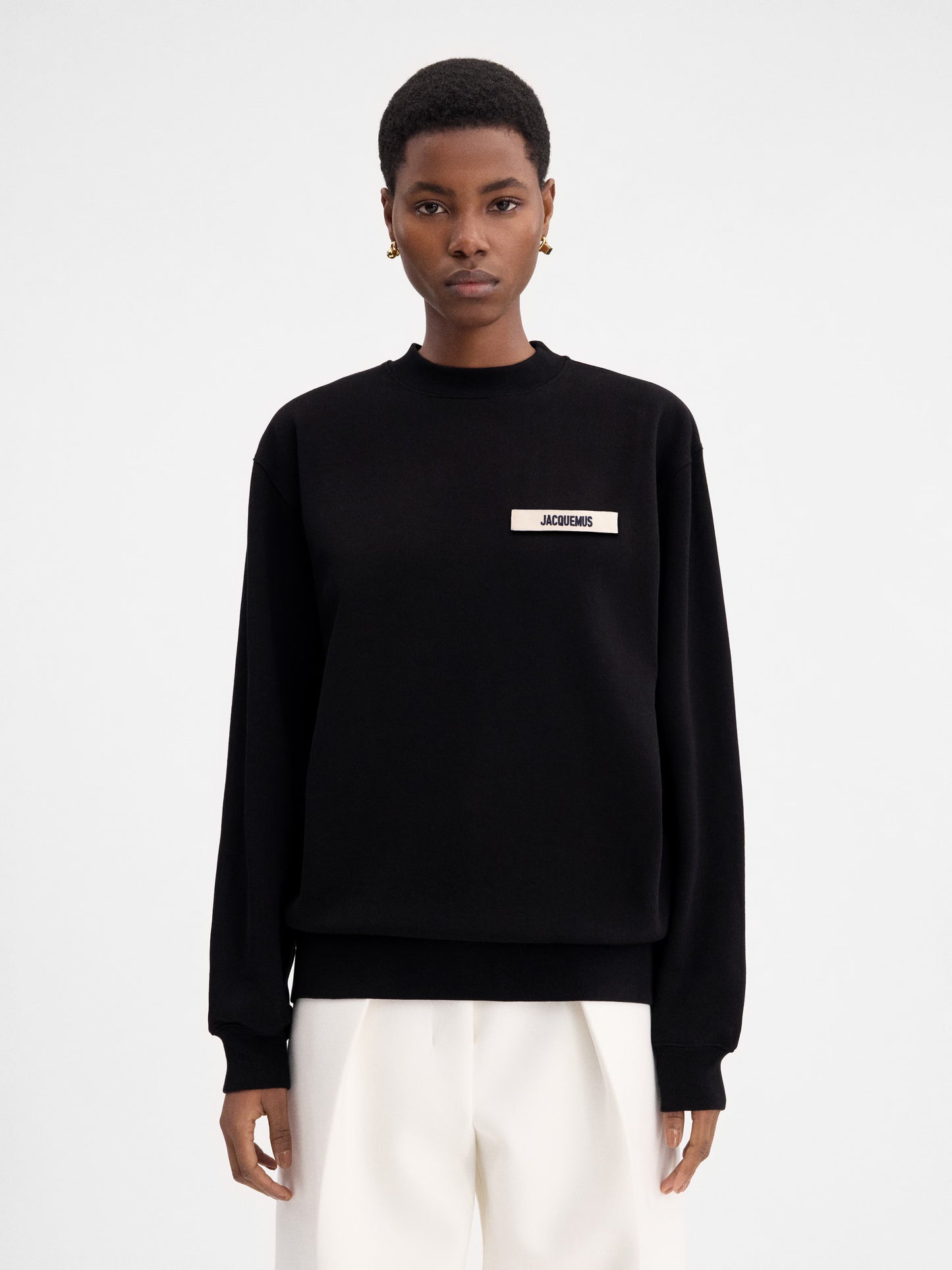 Person wearing a black sweatshirt with a logo on a white background