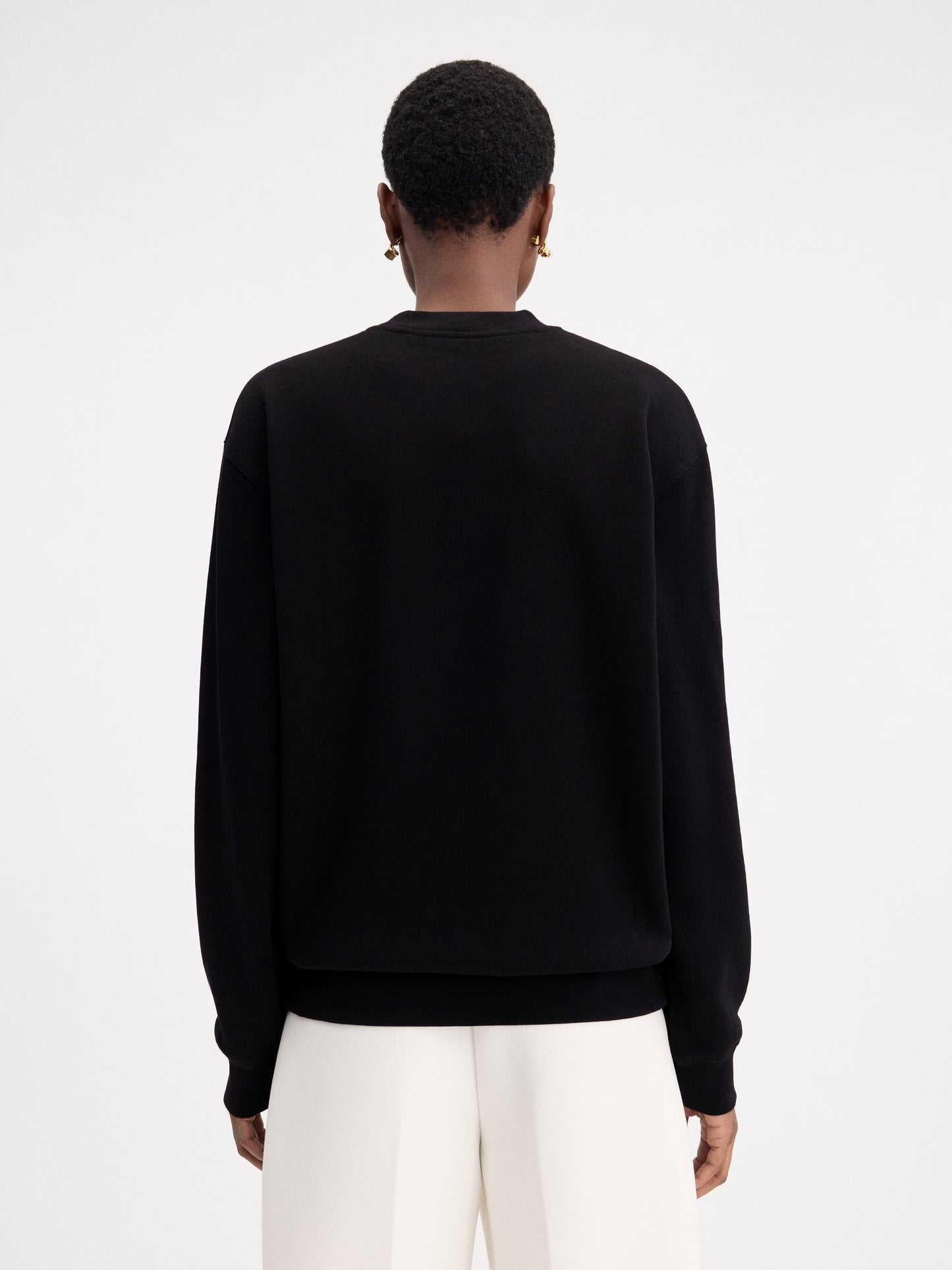 Person wearing a black sweatshirt with a logo on a white background