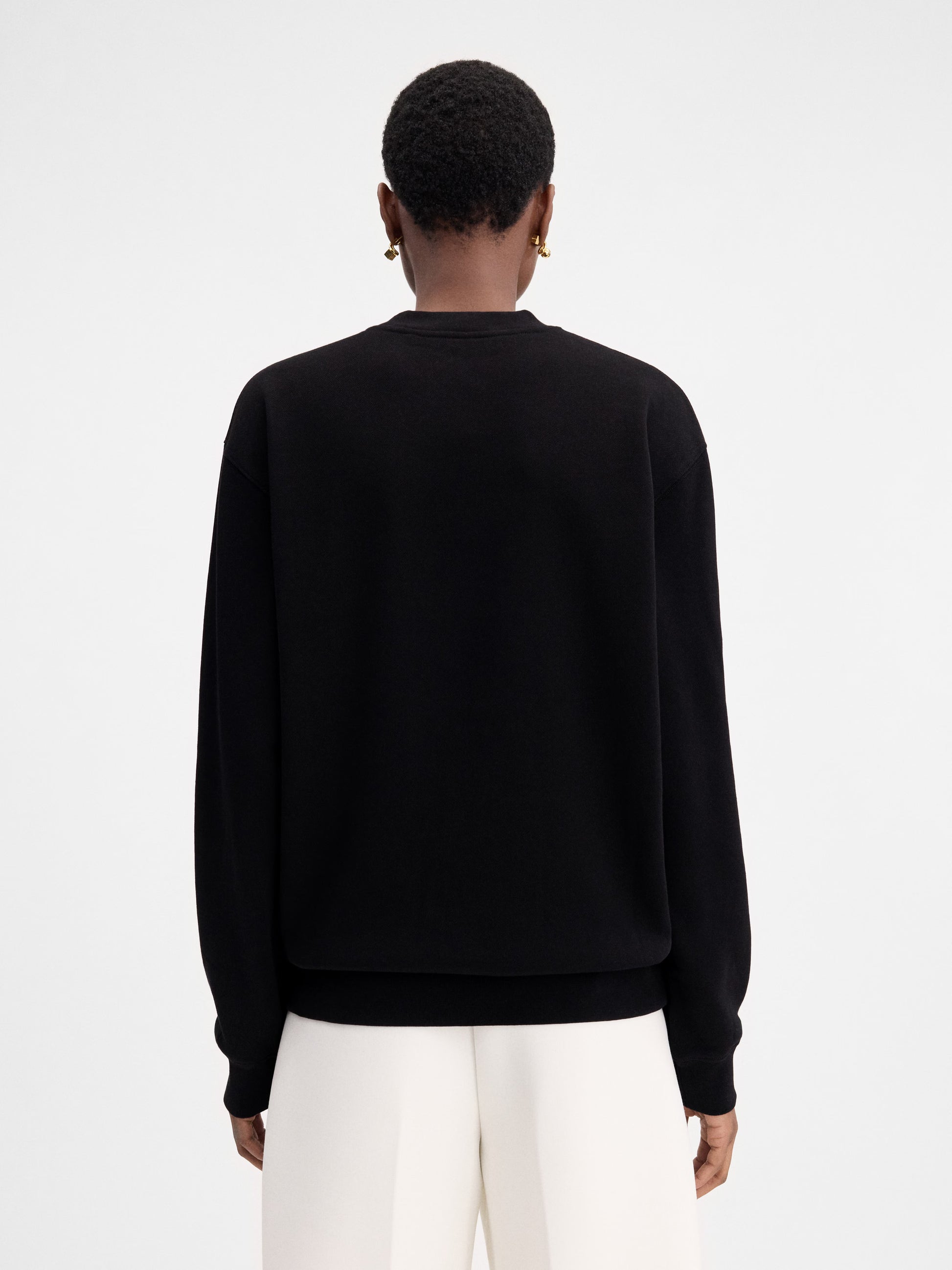 Person wearing a black sweatshirt with a logo on a white background