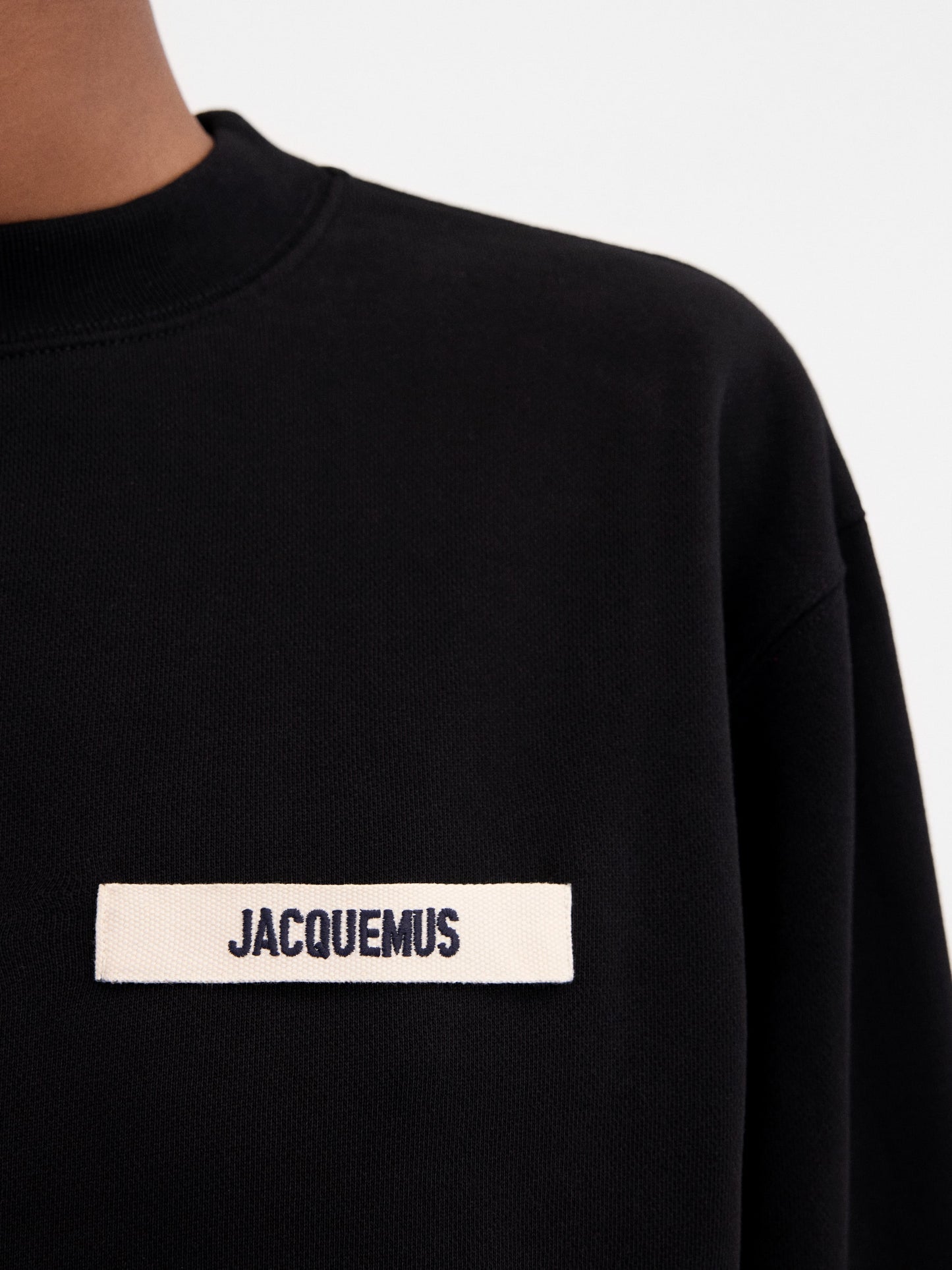 Person wearing a black sweatshirt with a logo on a white background