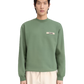 Person wearing a green sweatshirt with a logo on a white background