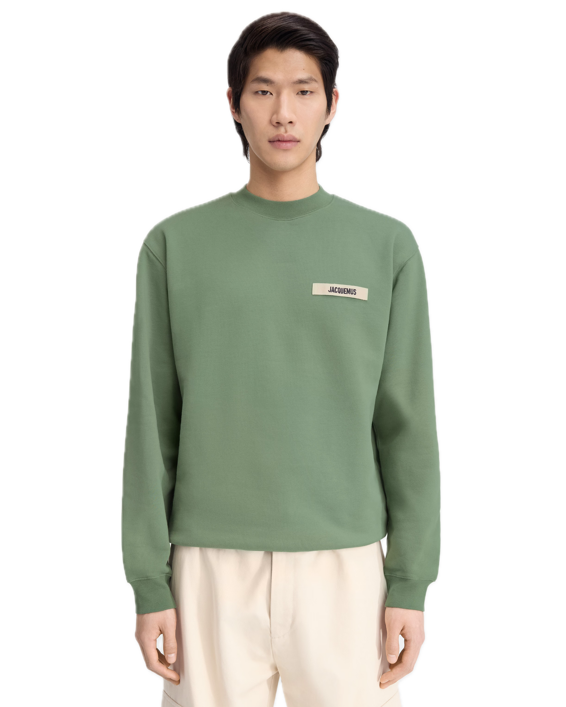Person wearing a green sweatshirt with a logo on a white background