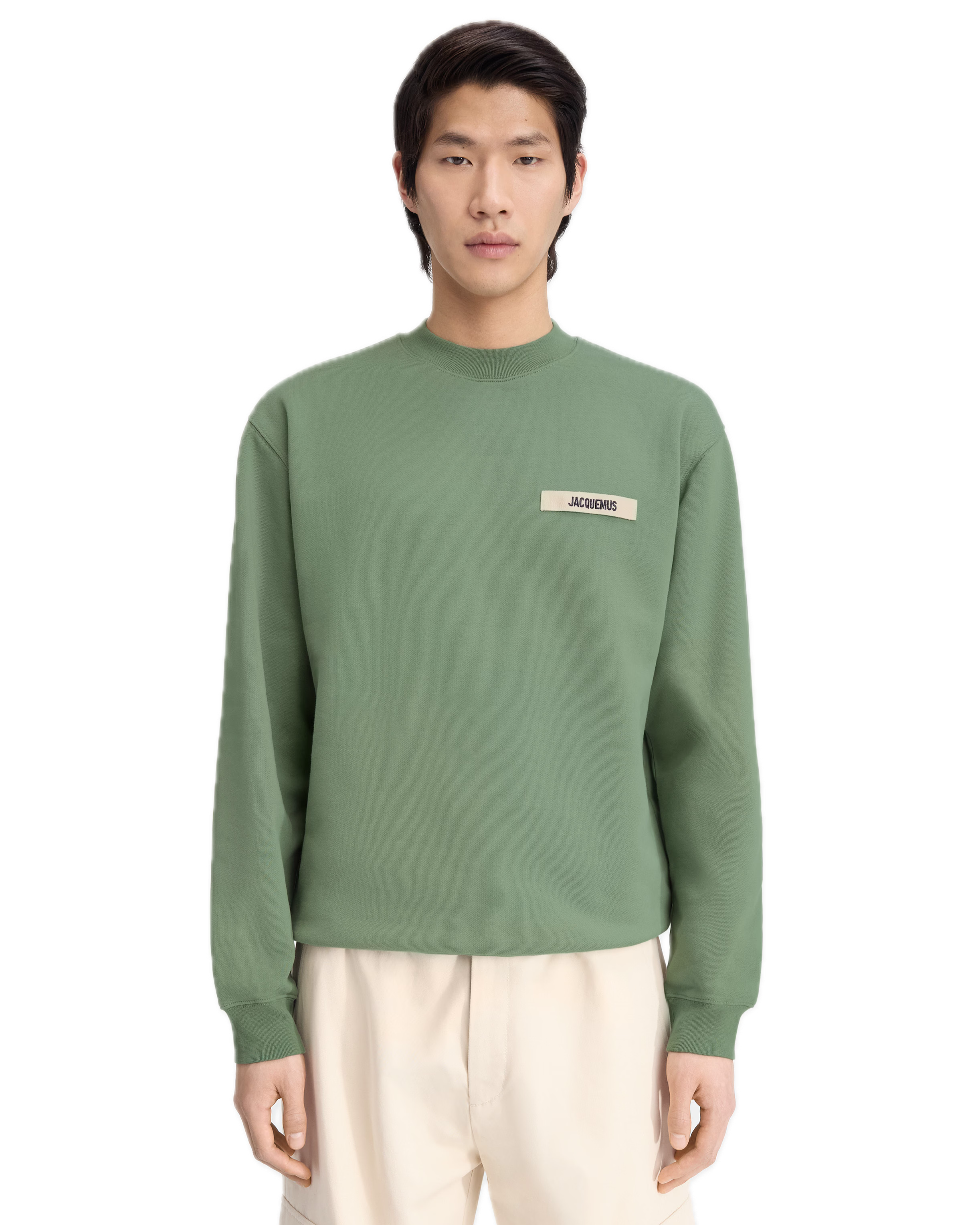 Person wearing a green sweatshirt with a logo on a white background