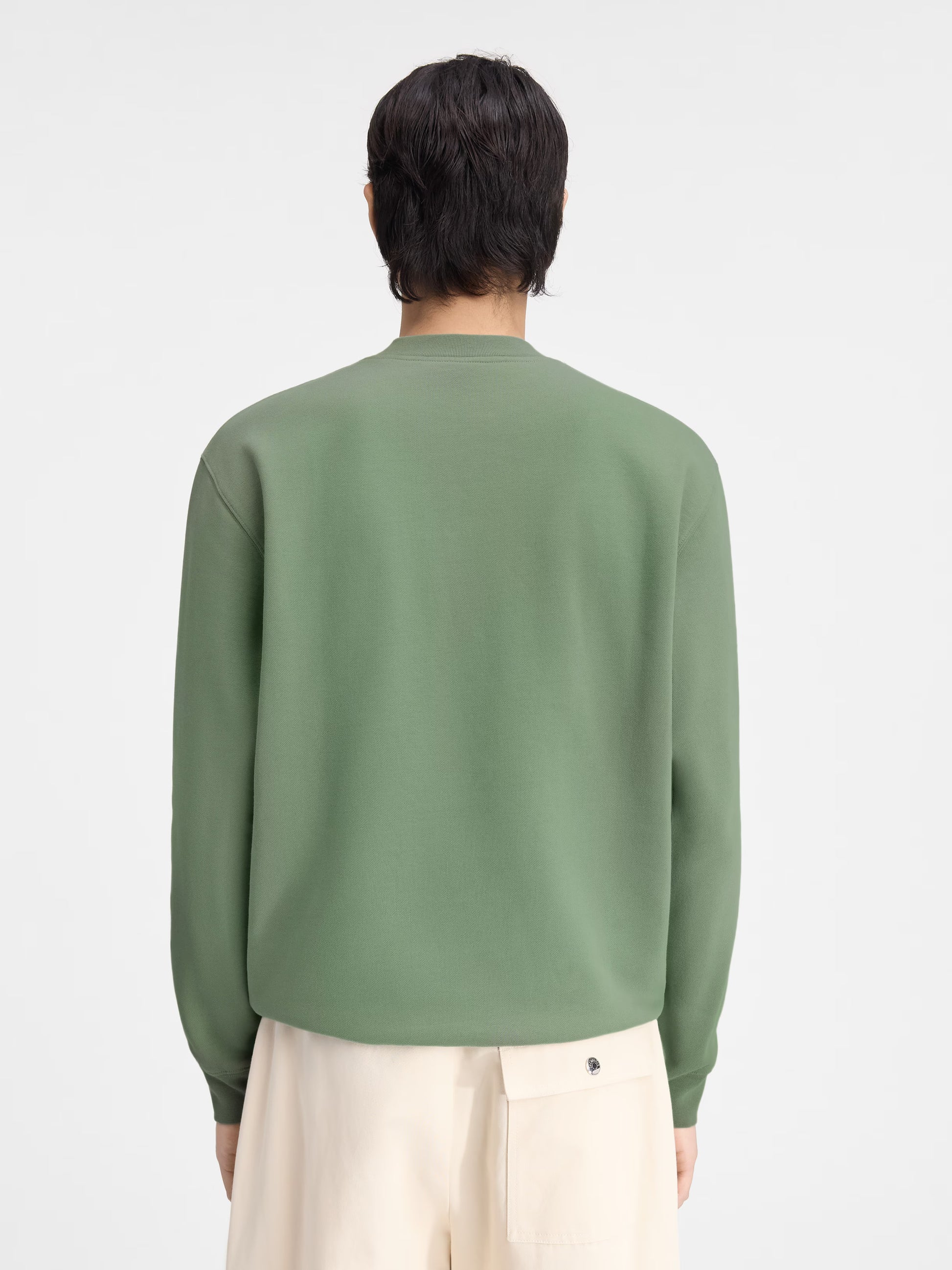 Person wearing a green sweatshirt with a logo on a white background