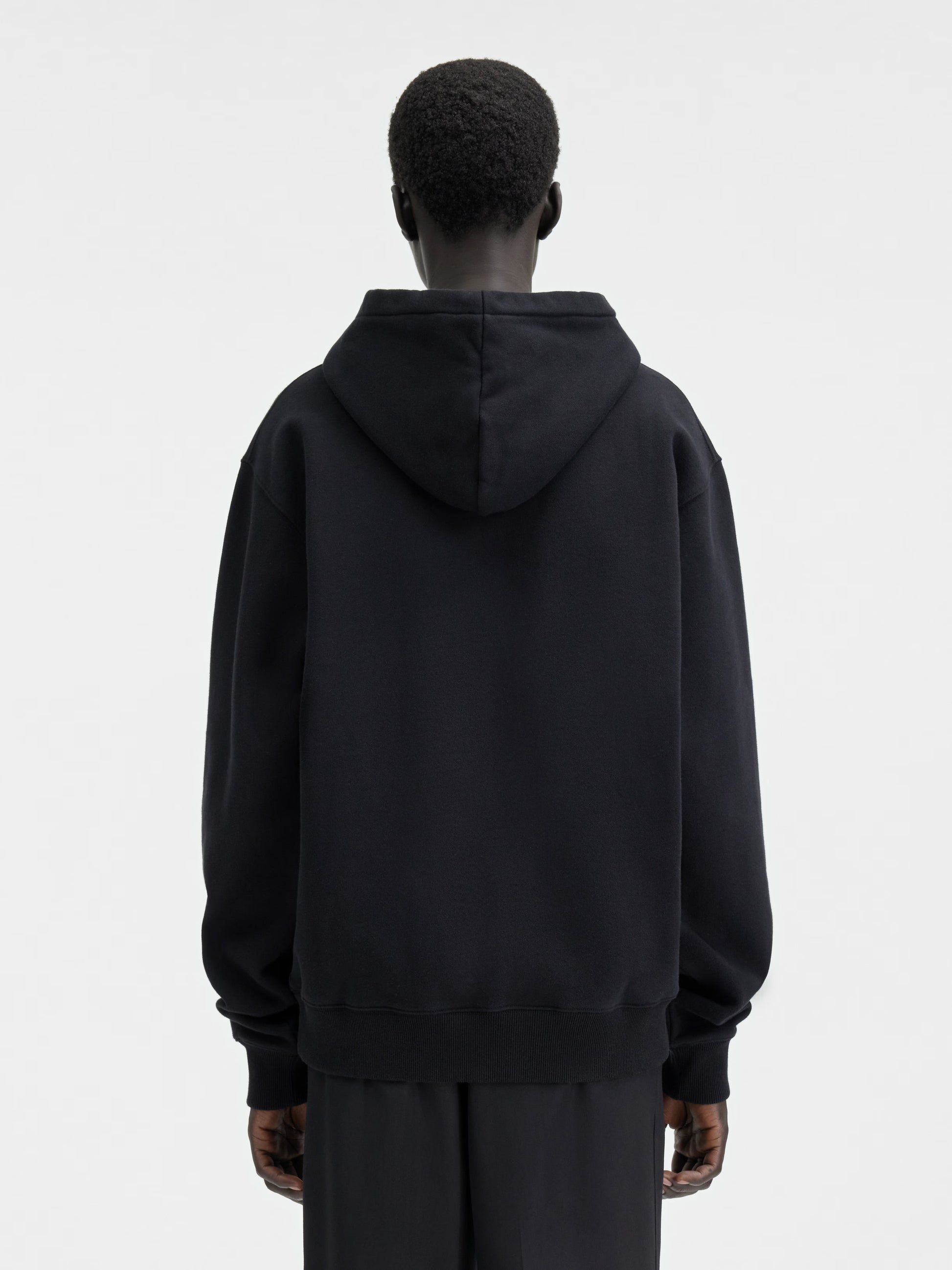 Person wearing a black hoodie with a brand logo on a white background