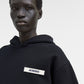 Person wearing a black hoodie with a brand logo on a white background