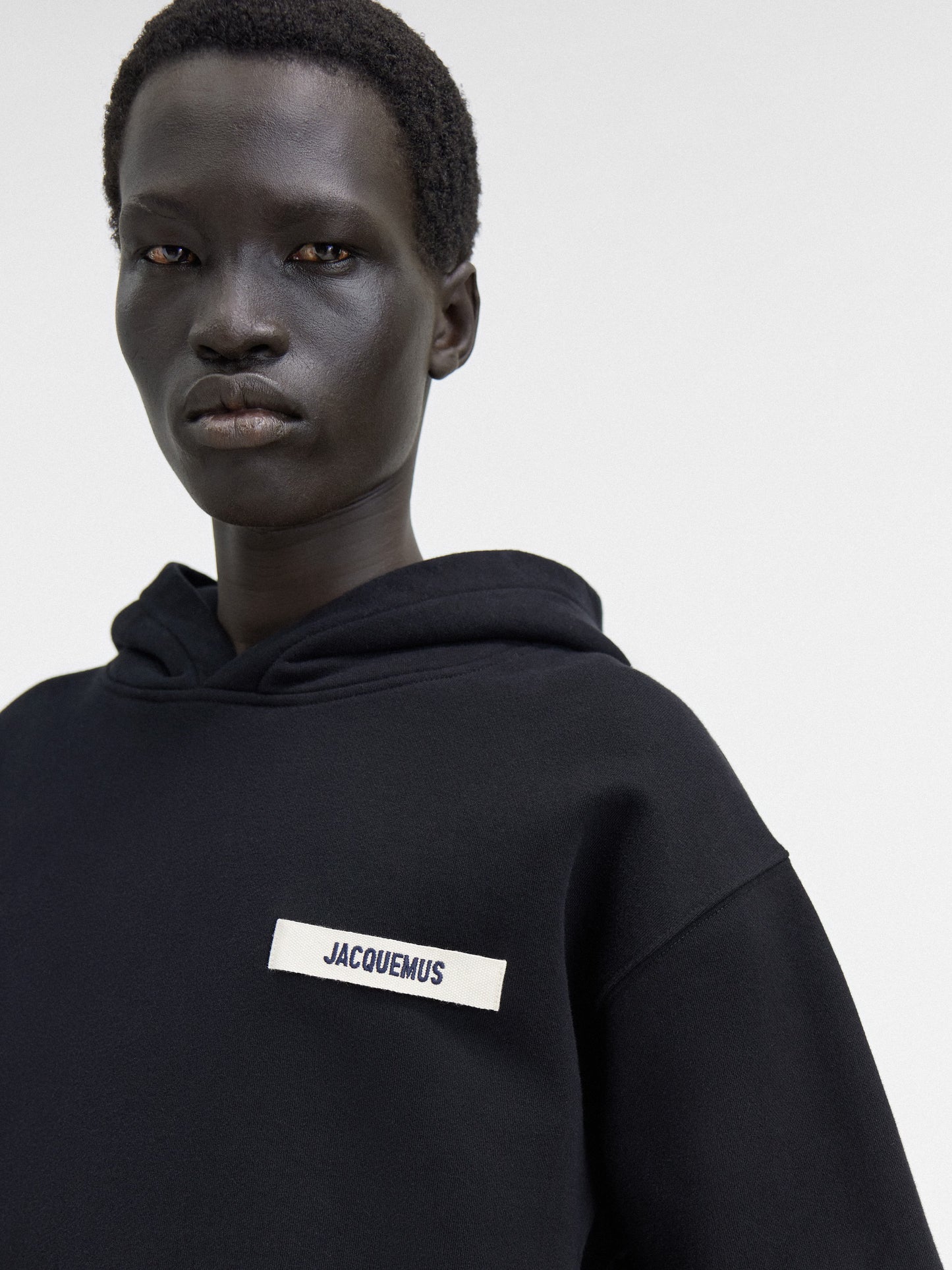 Person wearing a black hoodie with a brand logo on a white background