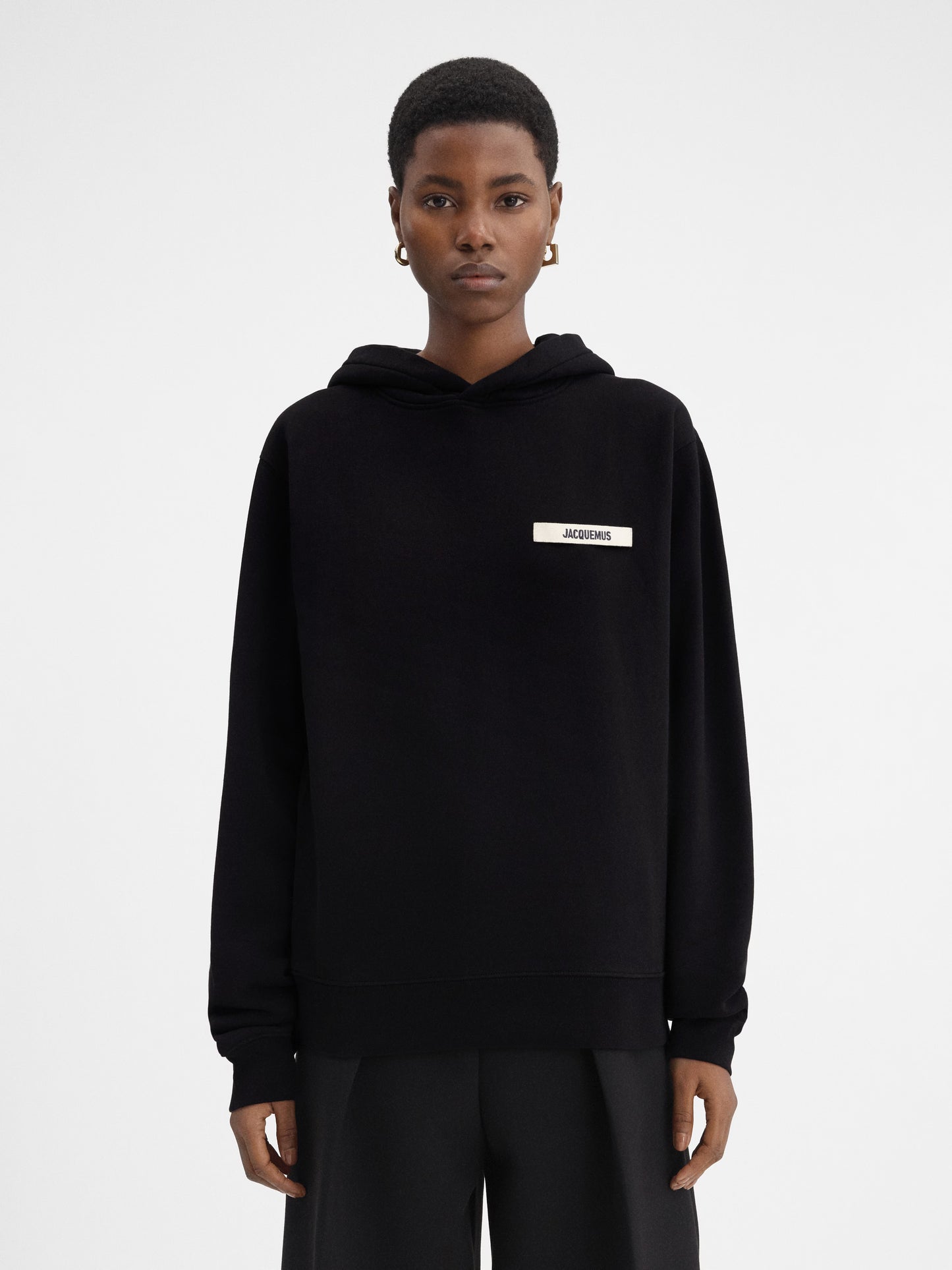 Person wearing a black hoodie with a brand logo on a white background