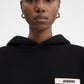 Person wearing a black hoodie with a brand logo on a white background