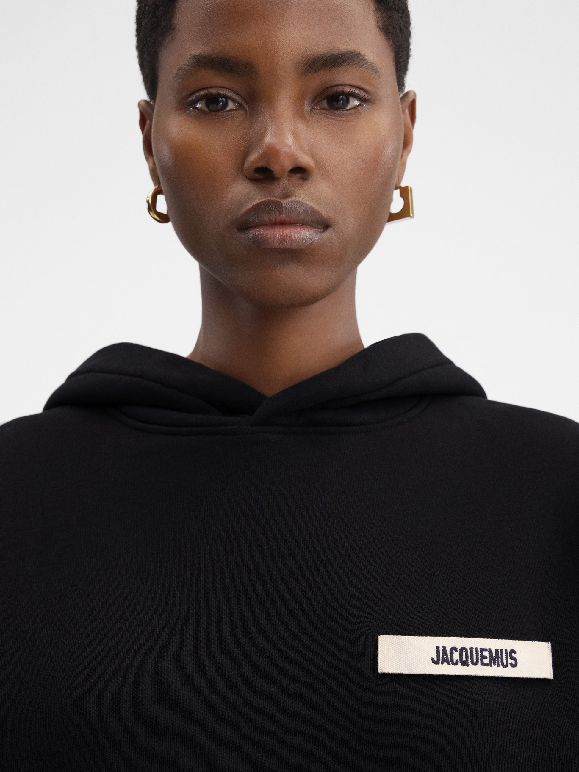 Person wearing a black hoodie with a brand logo on a white background