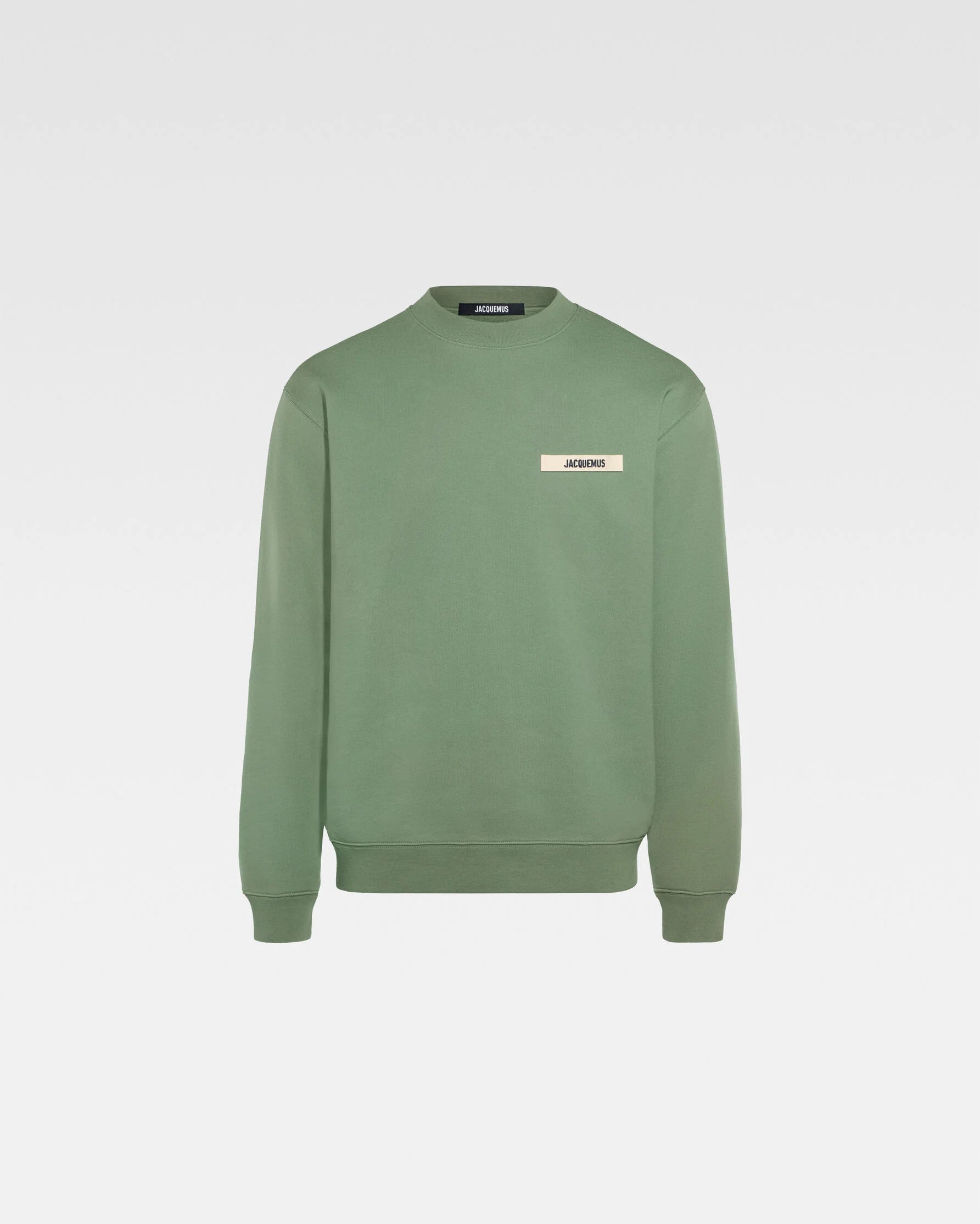 Person wearing a green sweatshirt with a logo on a white background