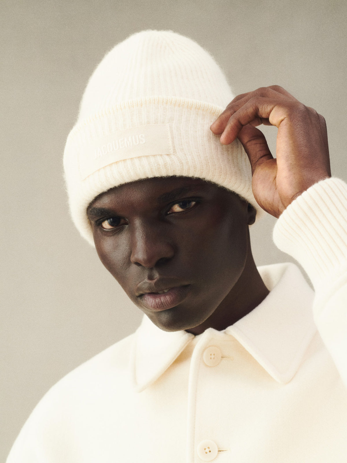 Beige knit sweater with 'Jacquemus' branding on a light background