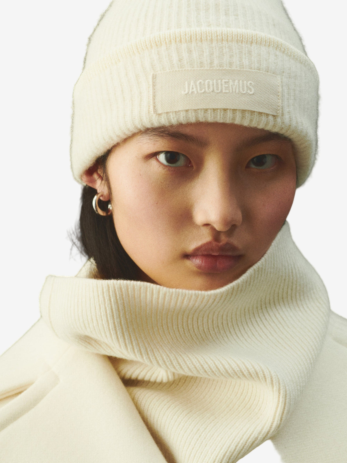Beige knit sweater with 'Jacquemus' branding on a light background
