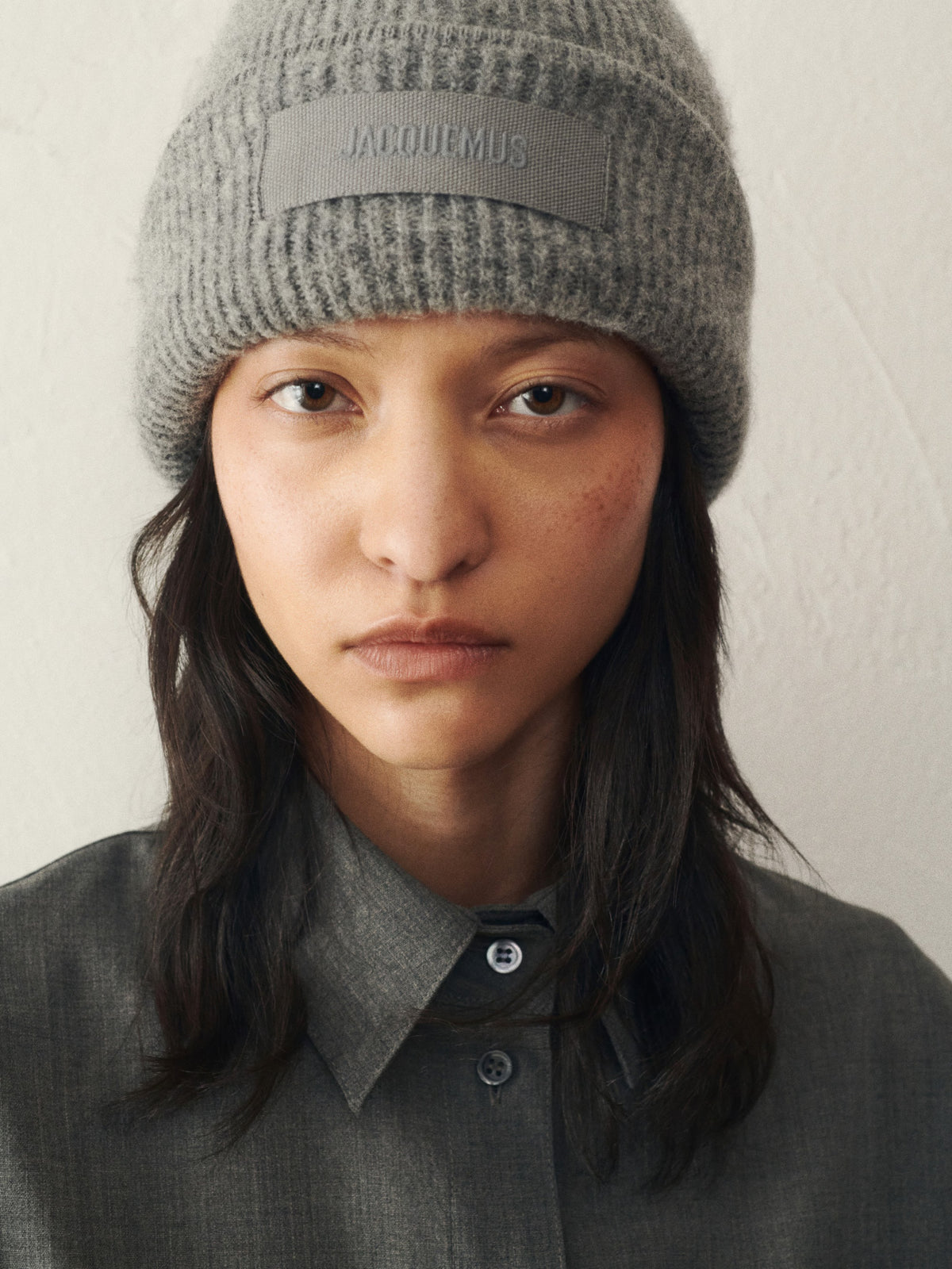 Gray knit beanie with a patch on a white background