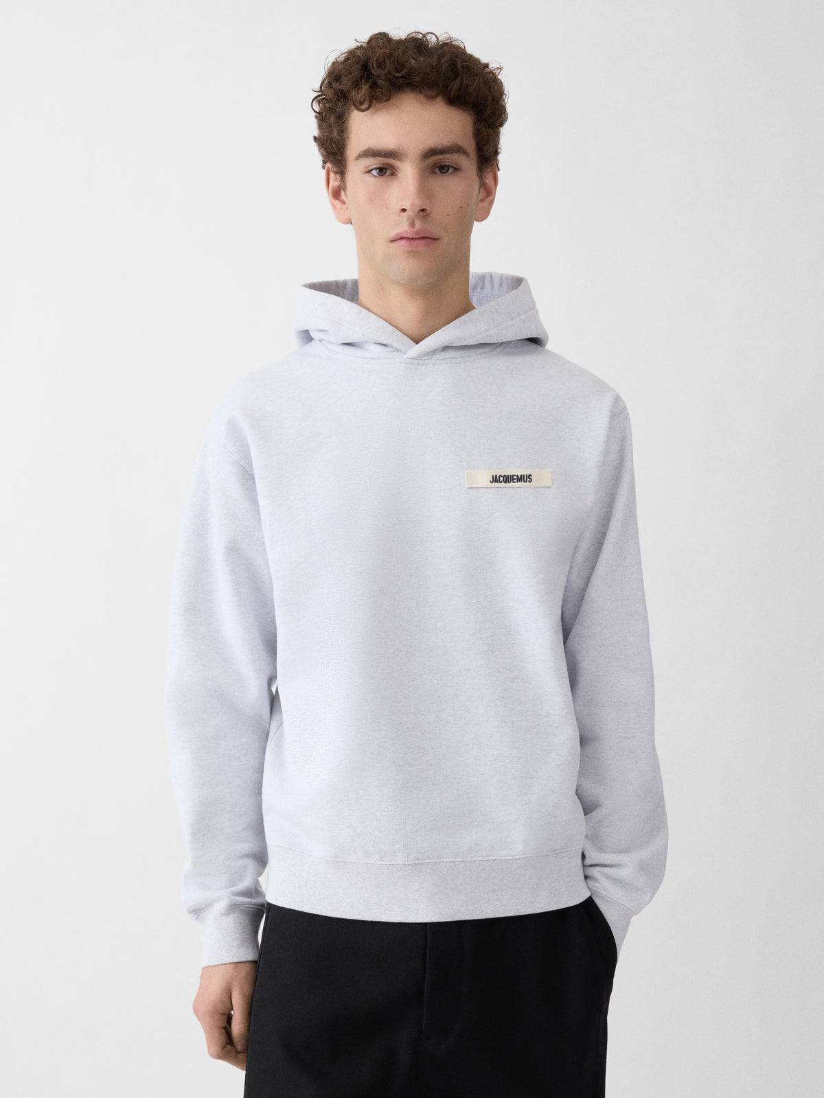 Grey hoodie with a small logo on the chest against a white background