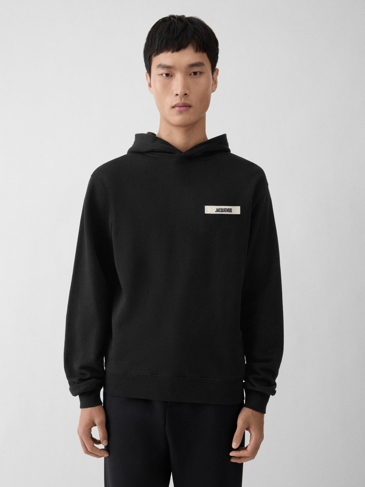 Black hoodie with a small logo on the chest against a white background