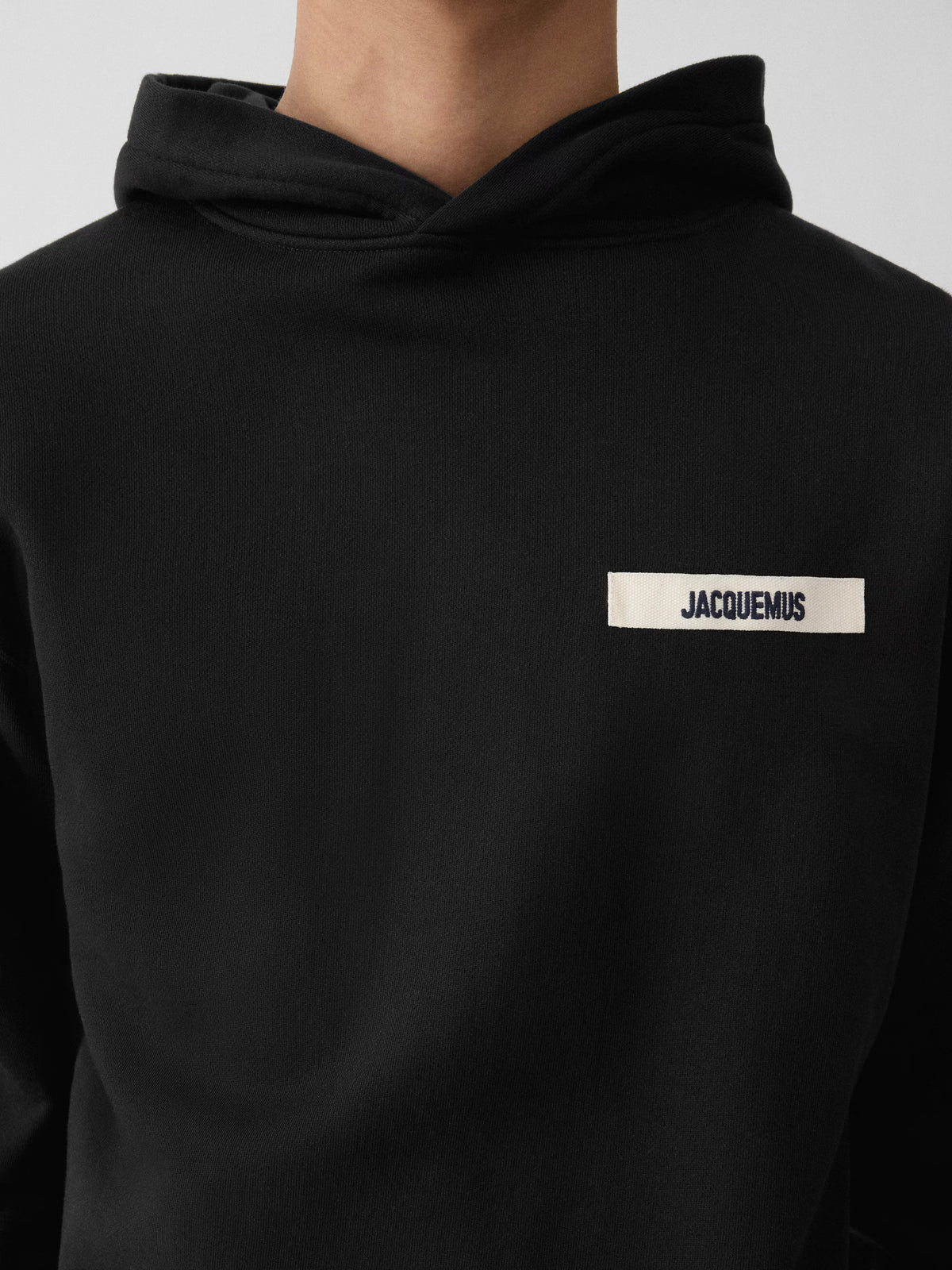 Black hoodie with a small logo on the chest against a white background