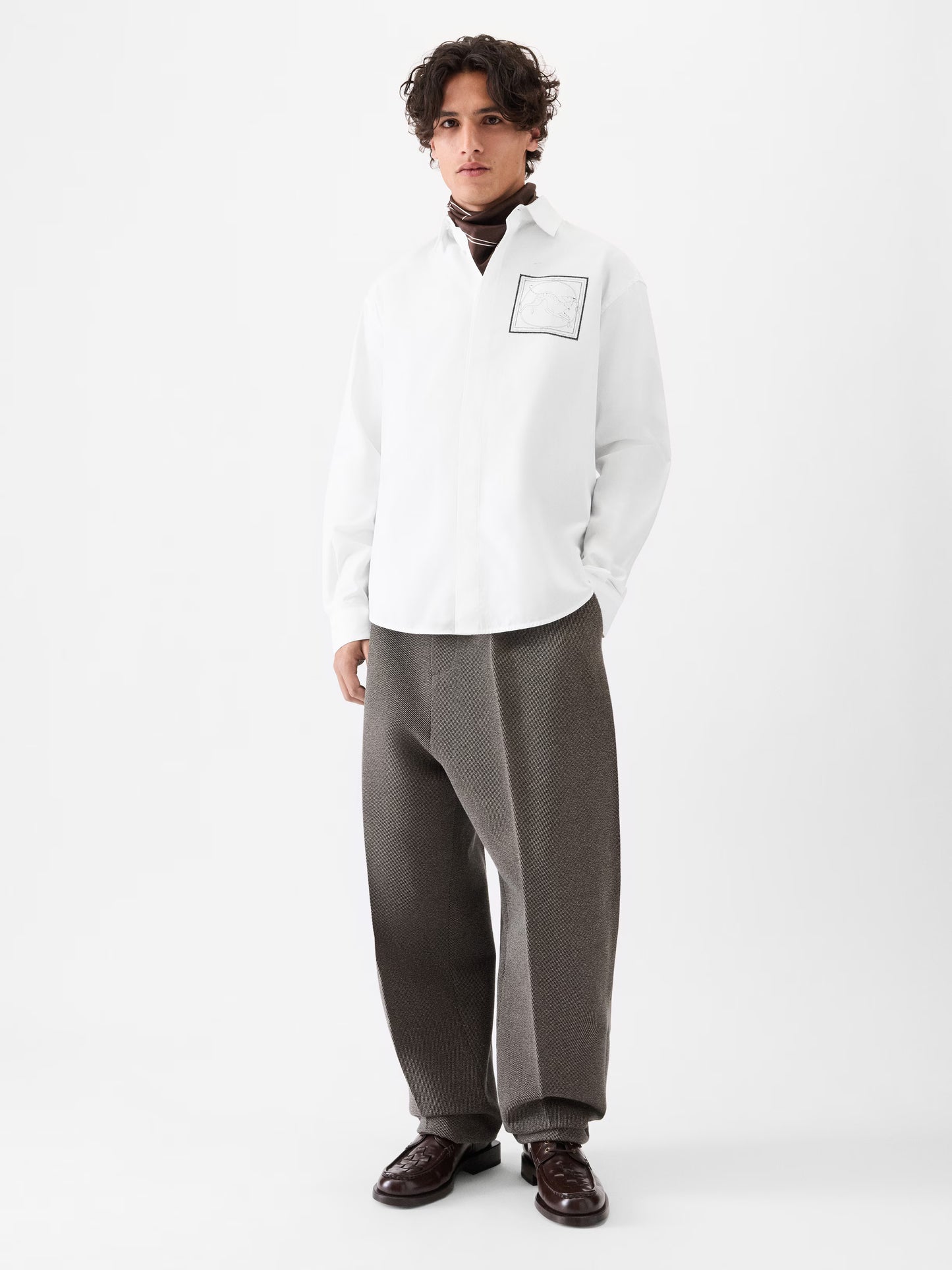 White shirt with a small black logo on the chest against a white background