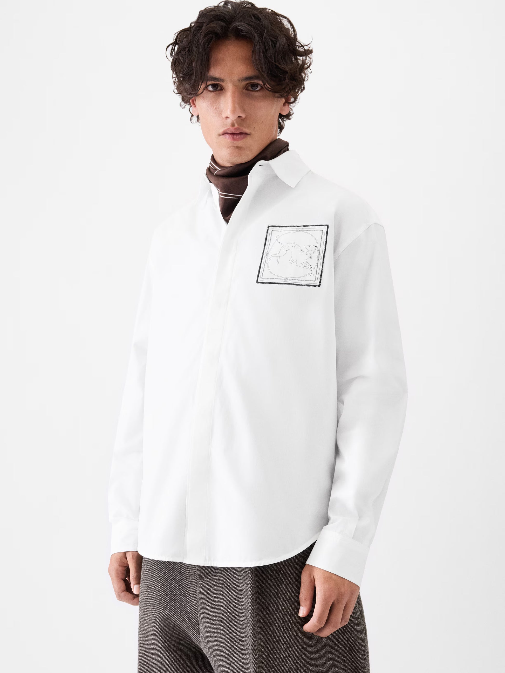 White shirt with a small black logo on the chest against a white background