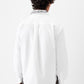 White shirt with a small black logo on the chest against a white background