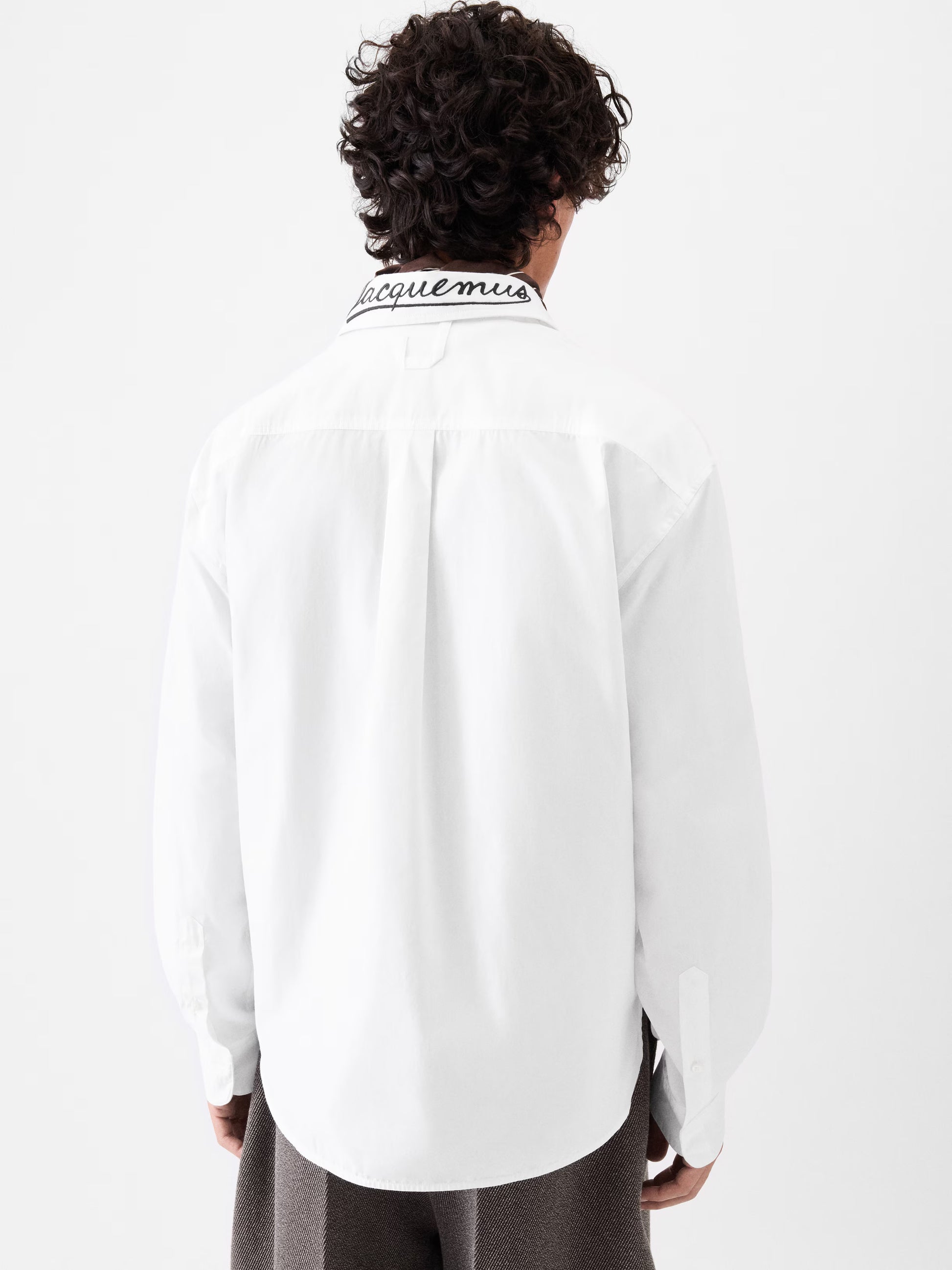 White shirt with a small black logo on the chest against a white background