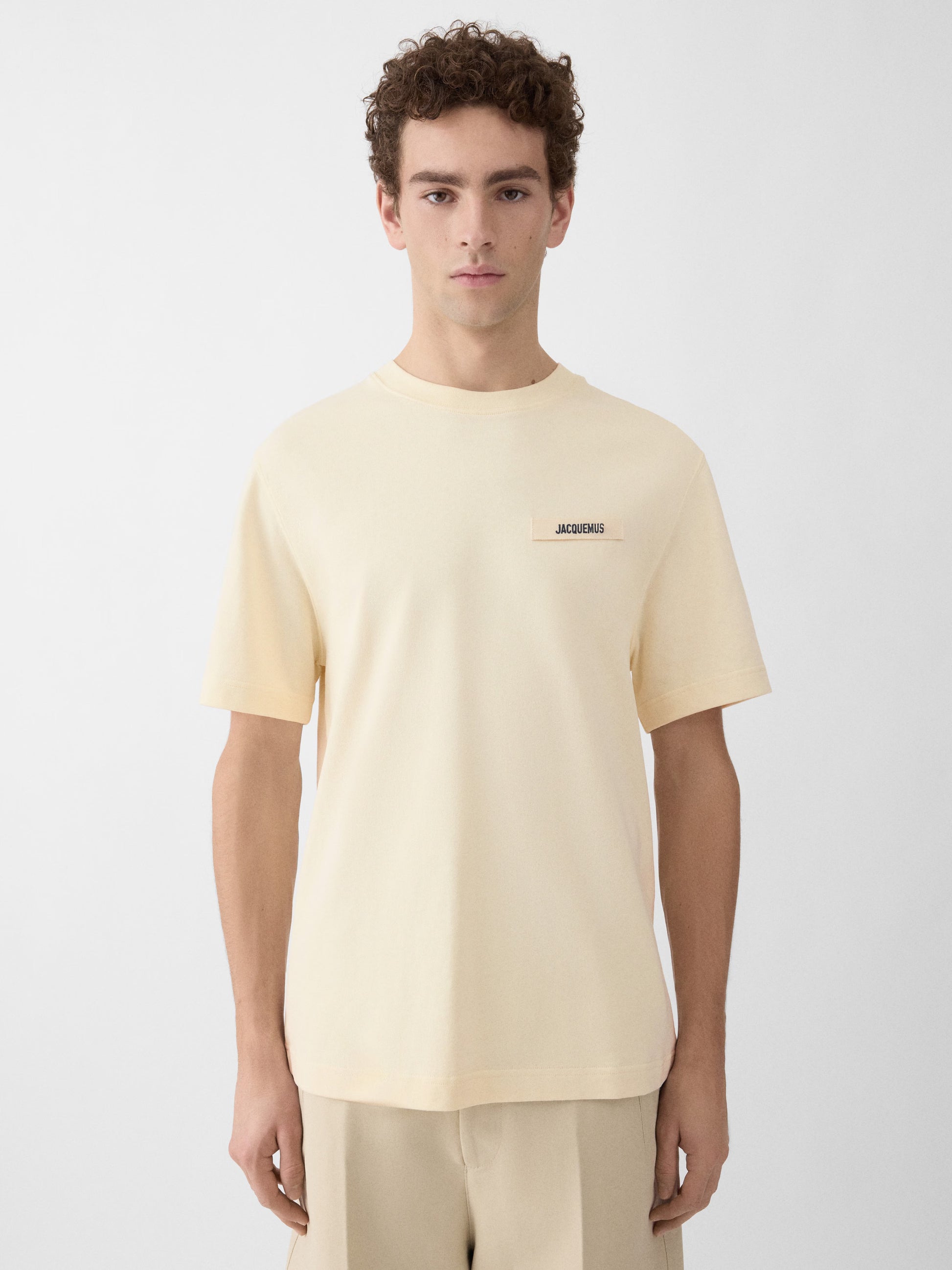 Beige t-shirt with a small logo on a white background