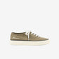 Green sneaker with white laces on a light beige background
