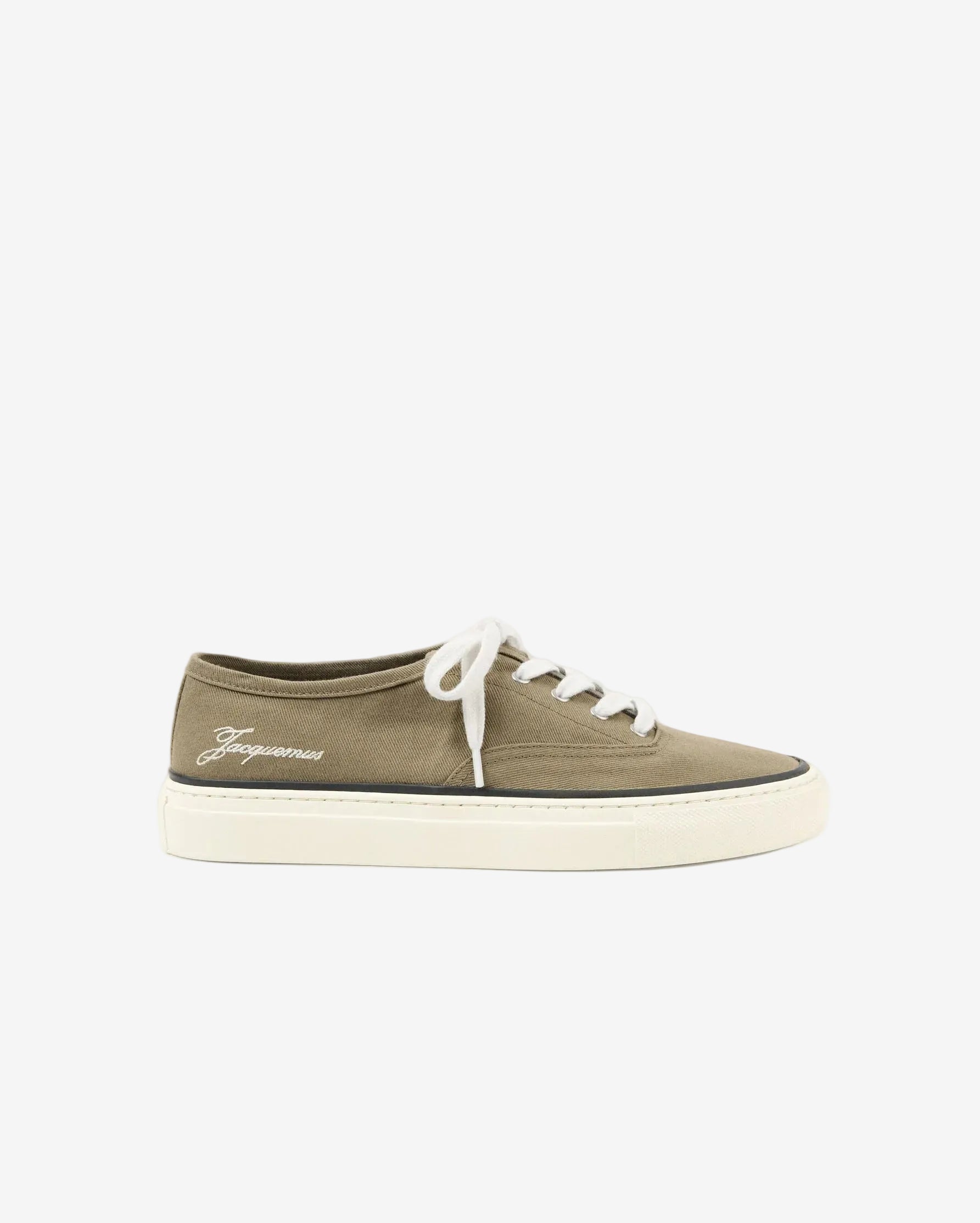 Green sneaker with white laces on a light beige background
