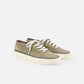 Green sneaker with white laces on a light beige background