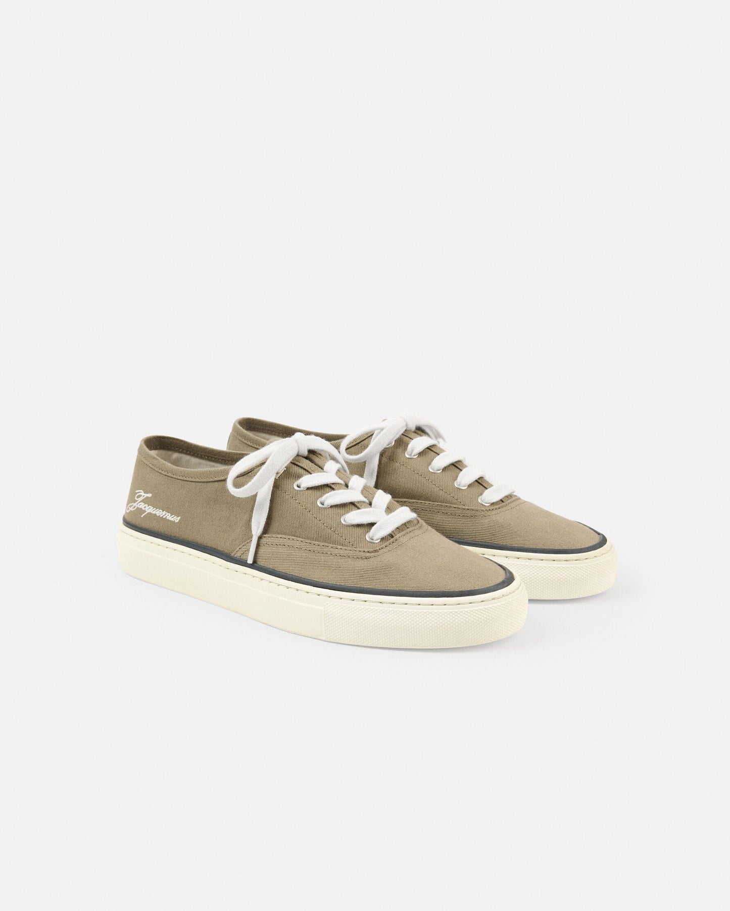 Green sneaker with white laces on a light beige background